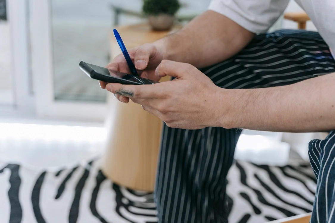 Close-up of a person holding a smartphone and pen