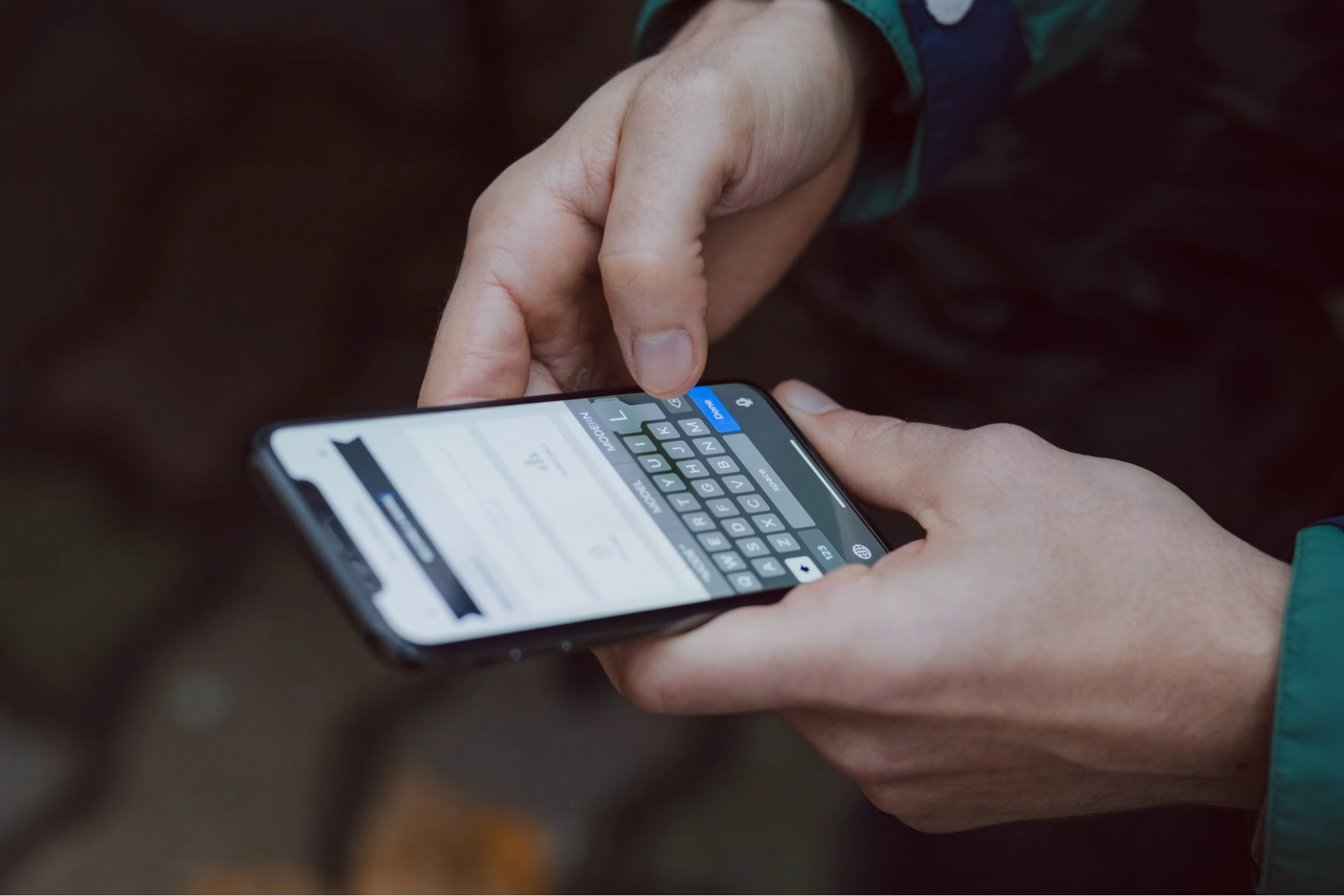 Close-up of hands typing on a smartphone