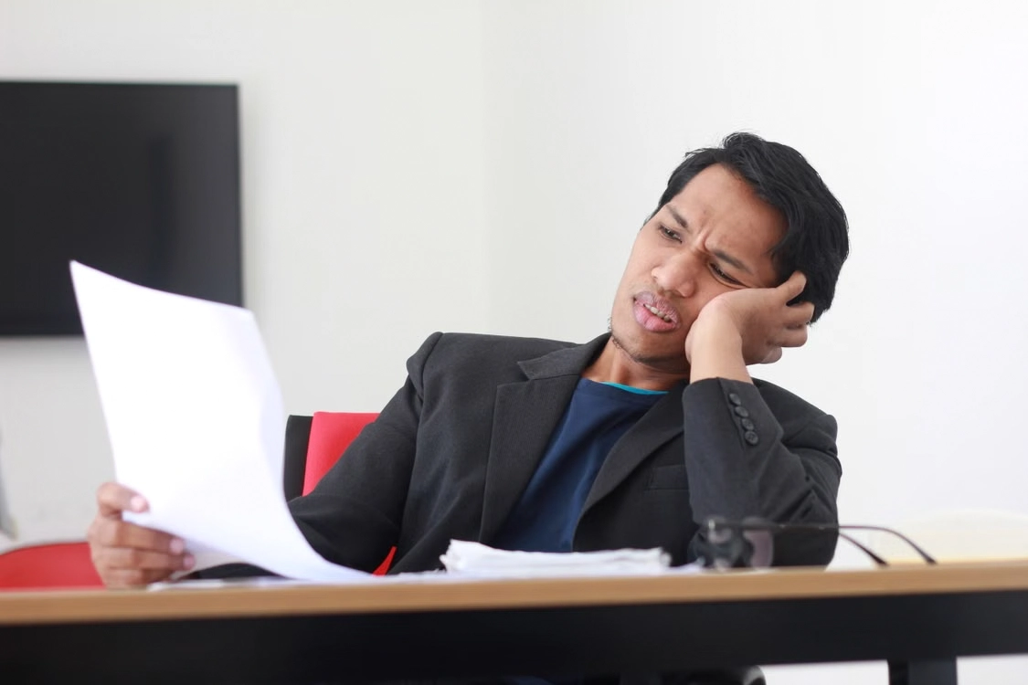 confused-man-looking-at-a-document-at-his-desk