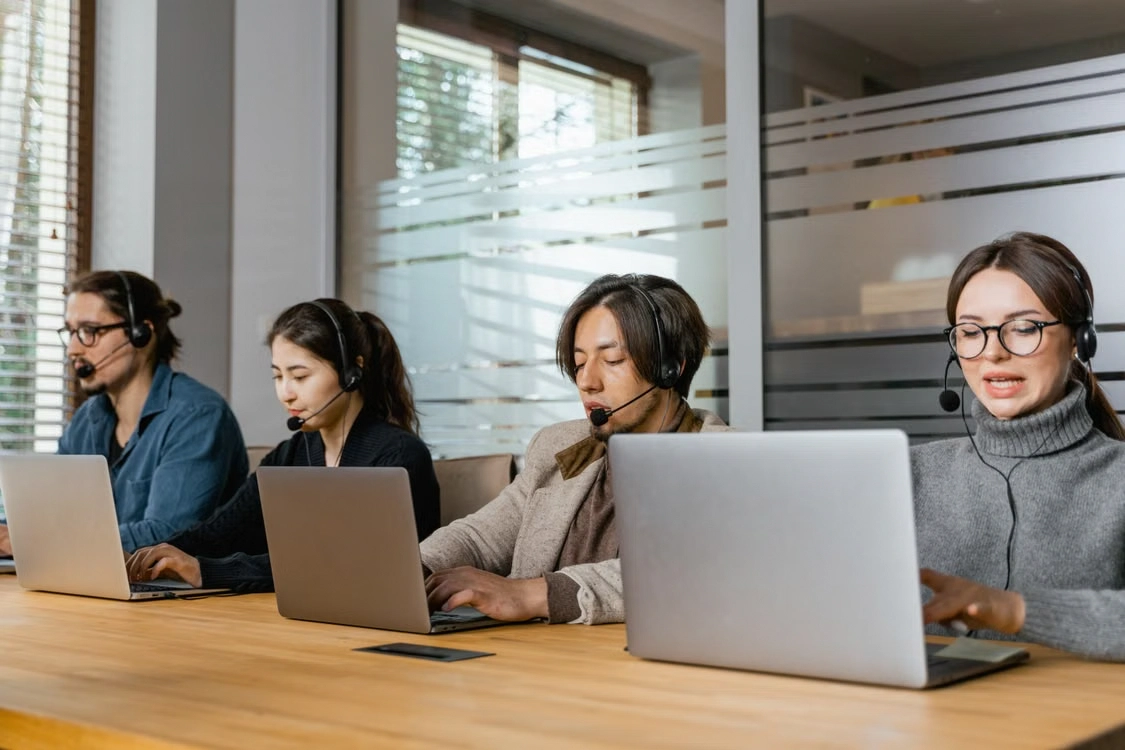 Customer service agents at laptops wearing headsets