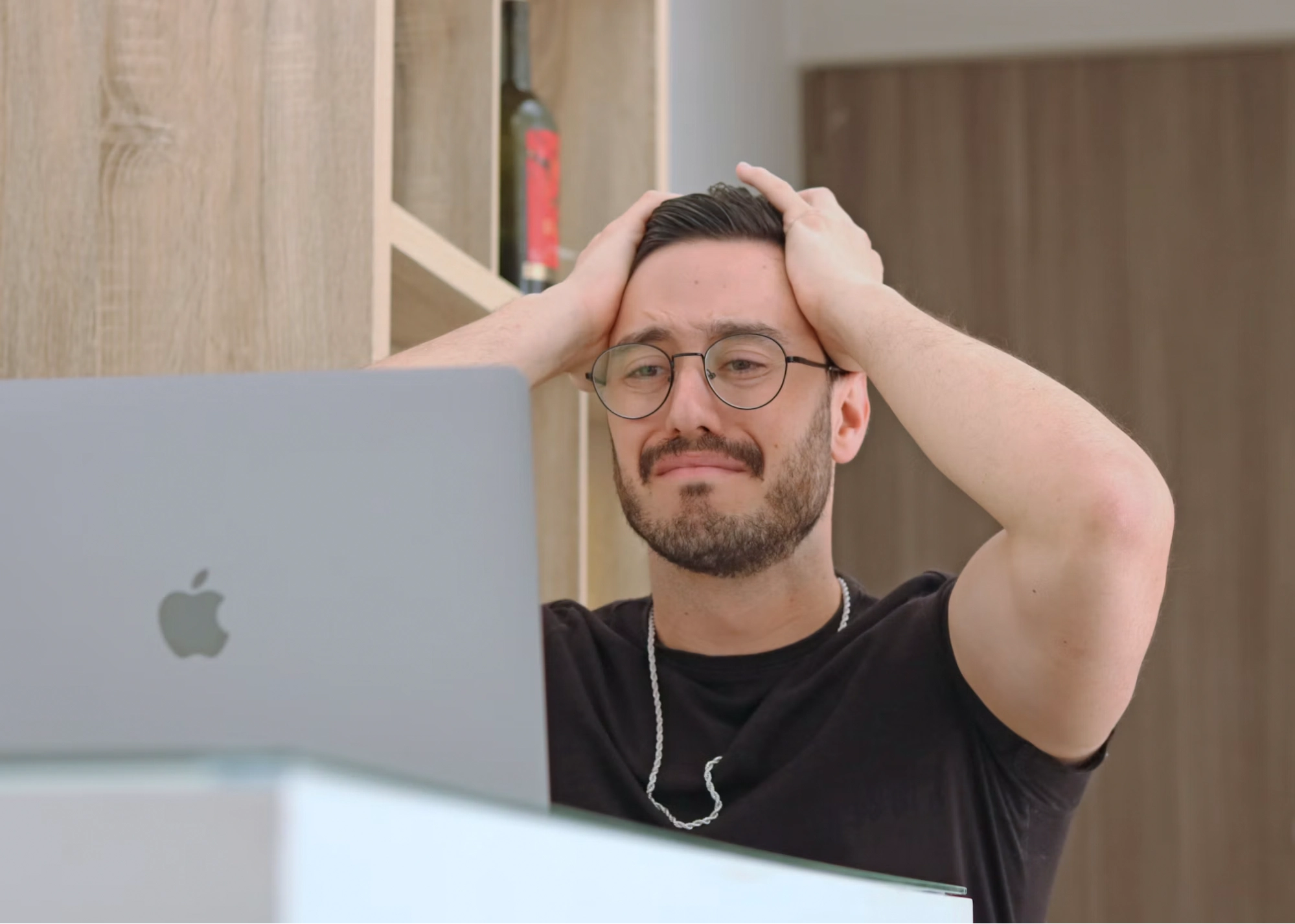 Frustrated man holding his head in front of a laptop