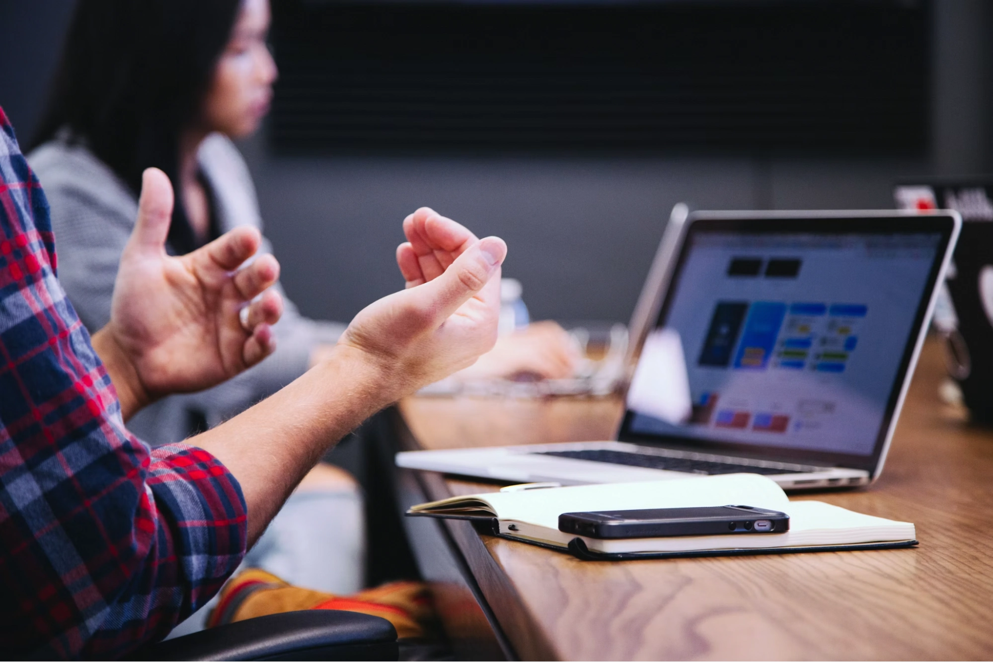 Person gesturing while talking at a desk with a laptop