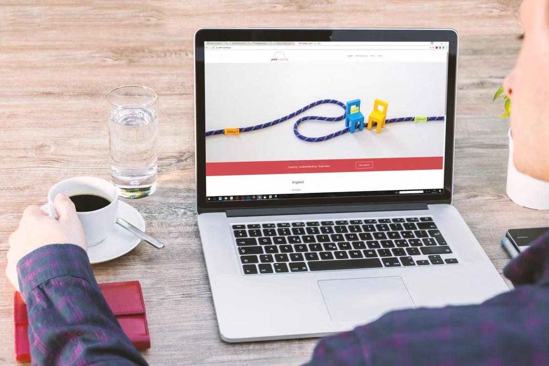 Person holding coffee cup while working on a laptop