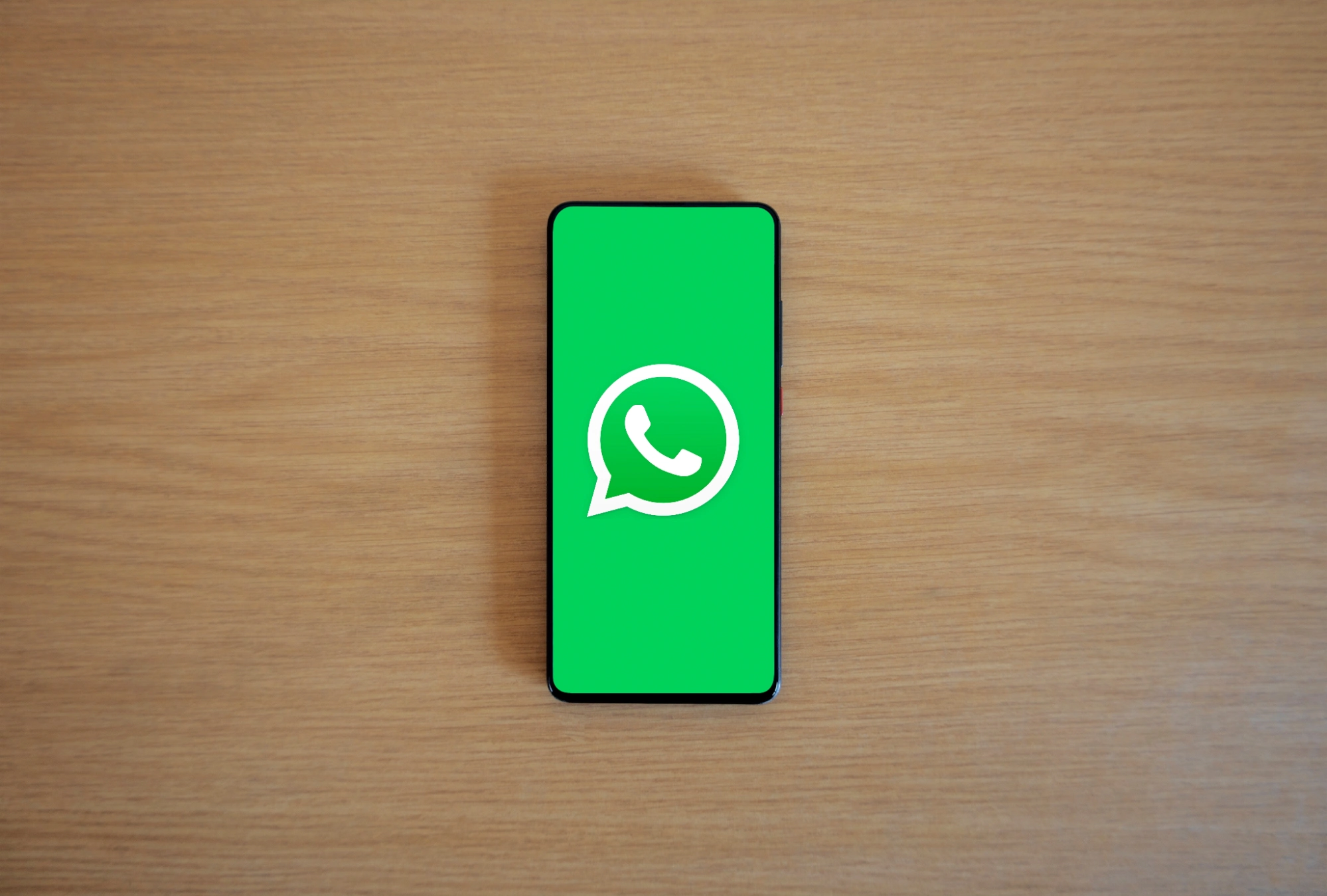 Smartphone displaying the WhatsApp icon on a table