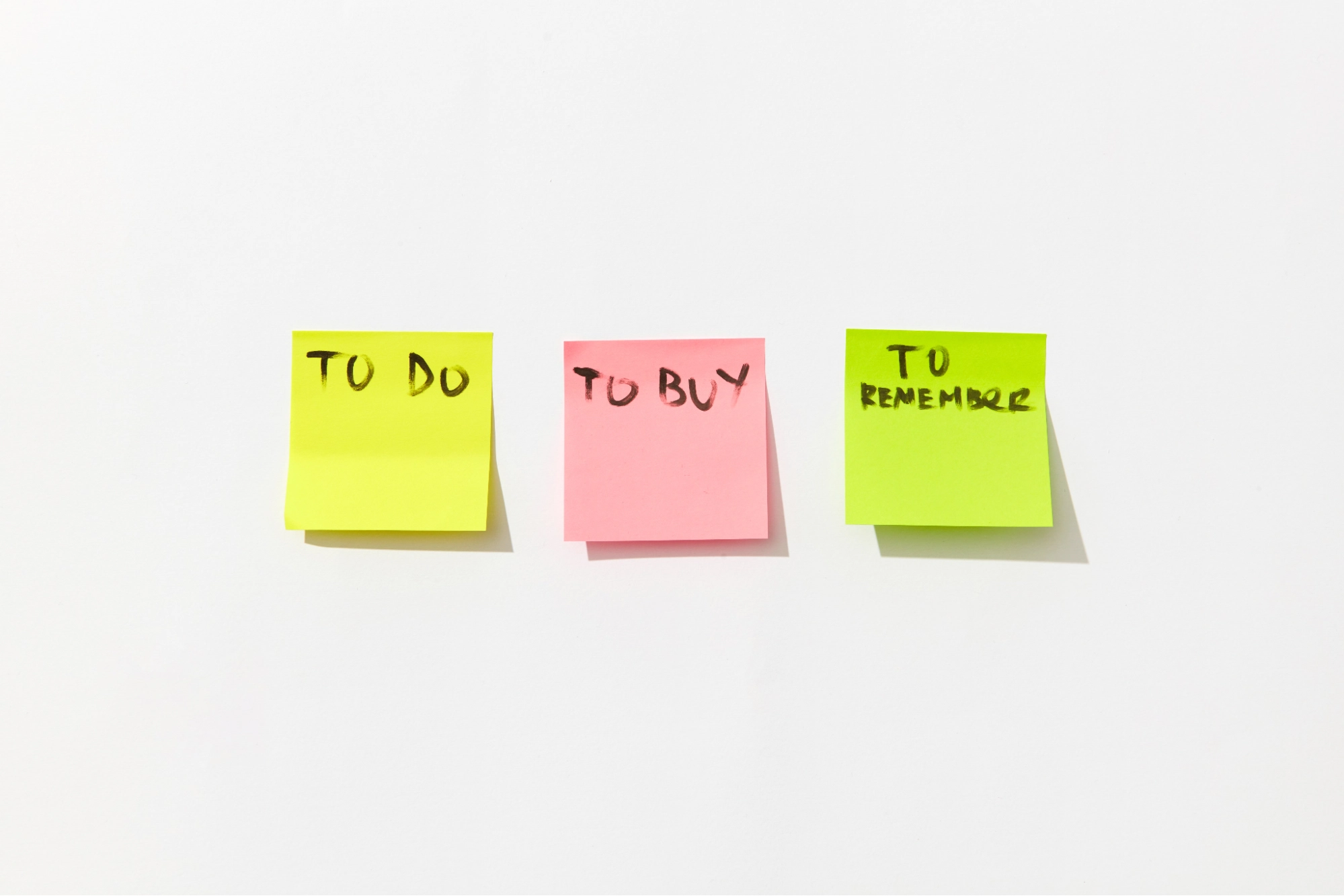 Three colorful sticky notes with handwritten text To Do To Buy and To Remember